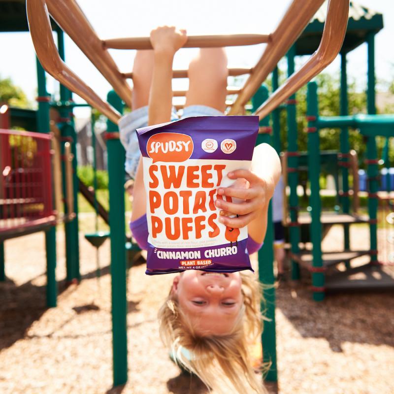 child holding Spudsy Sweet Potato Puffs on the monkey bars